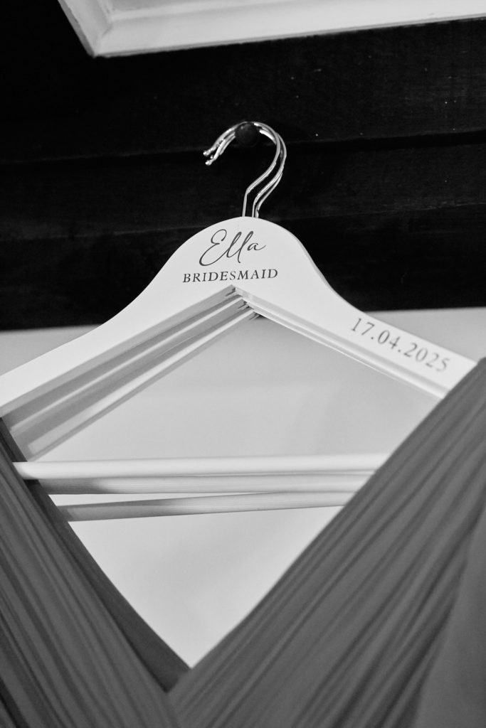 Black and white photo of a bridesmaid dress on a personalised wooden hanger