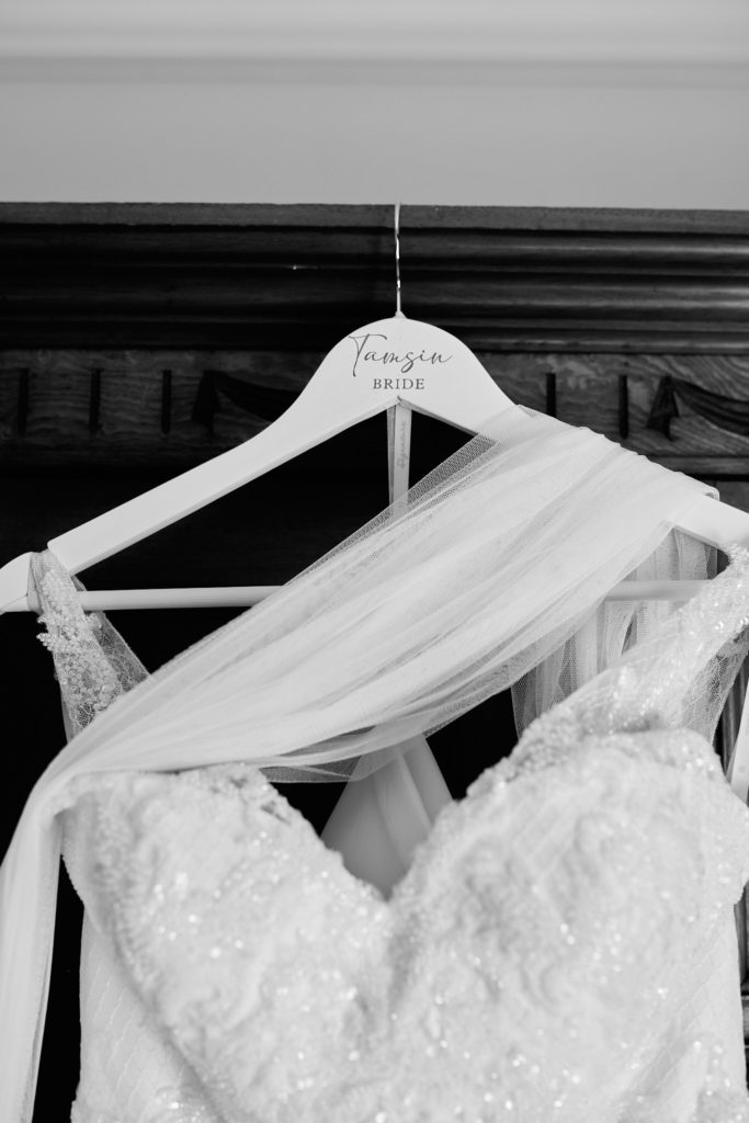 Black and white photo of a wedding dress and veil on a personalised hanger