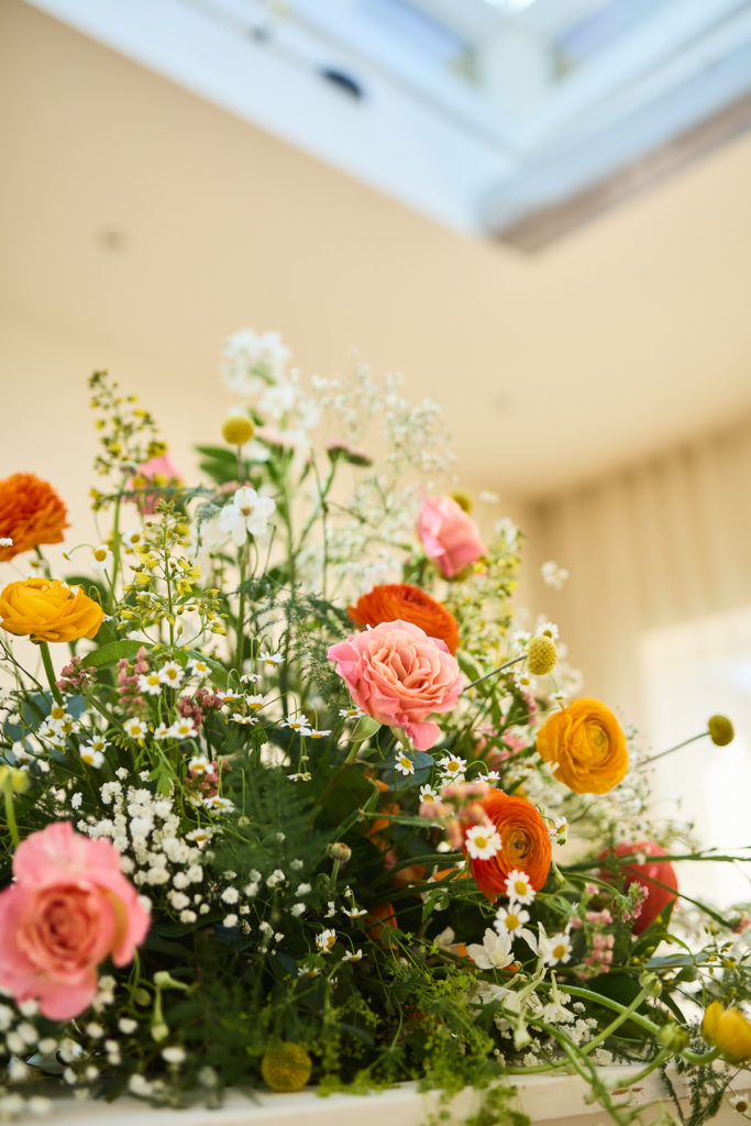 Arrangement of pink roses, orange ranunculus and wildflowers