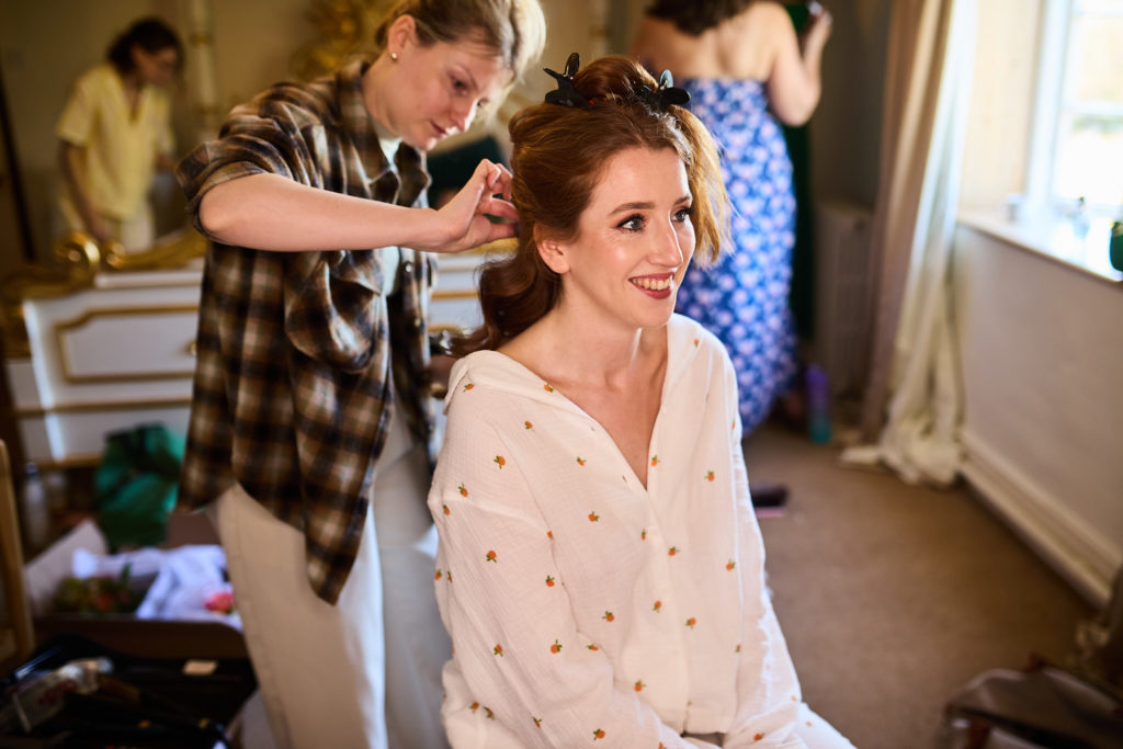 Bride smiling as a stylist pins her hair