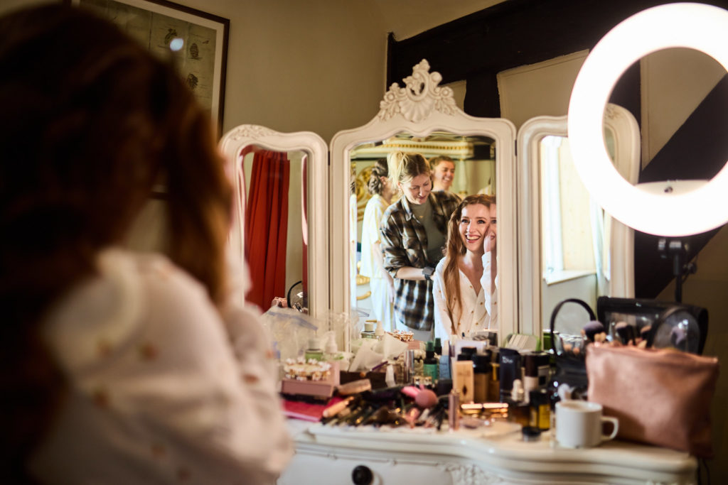 Bridal prep reflected in a dressing table mirror with a ring light