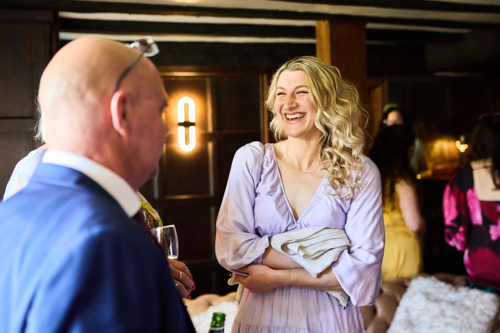 Wedding guest in a lilac dress laughing with a man in a blue suit