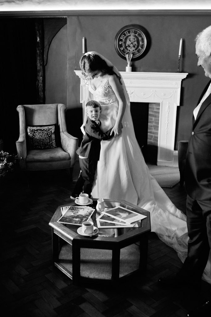 Black and white photo of a bride in her wedding dress in a sitting room at Prested Hall