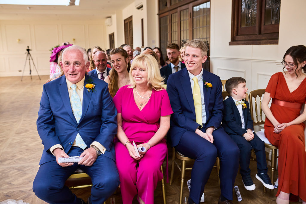 Wedding guests smiling as they watch the ceremony
