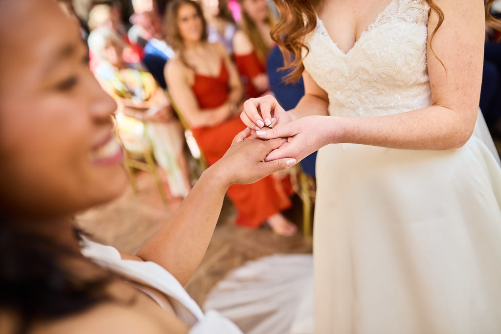 Close-up of a bride placing a wedding ring on her wife's finger