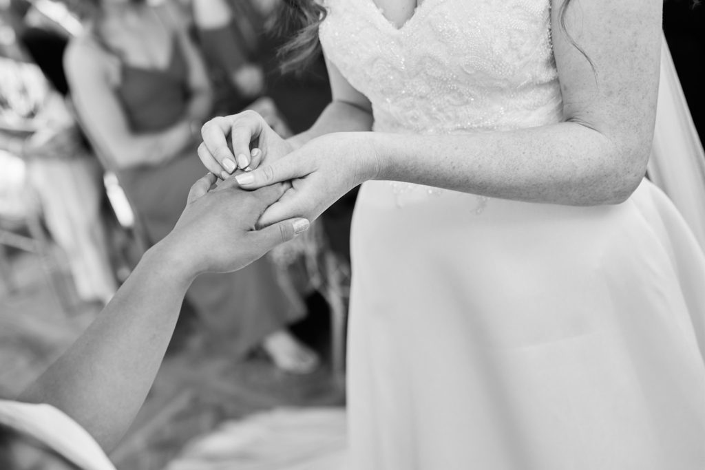 Black and white close-up of the brides exchanging rings