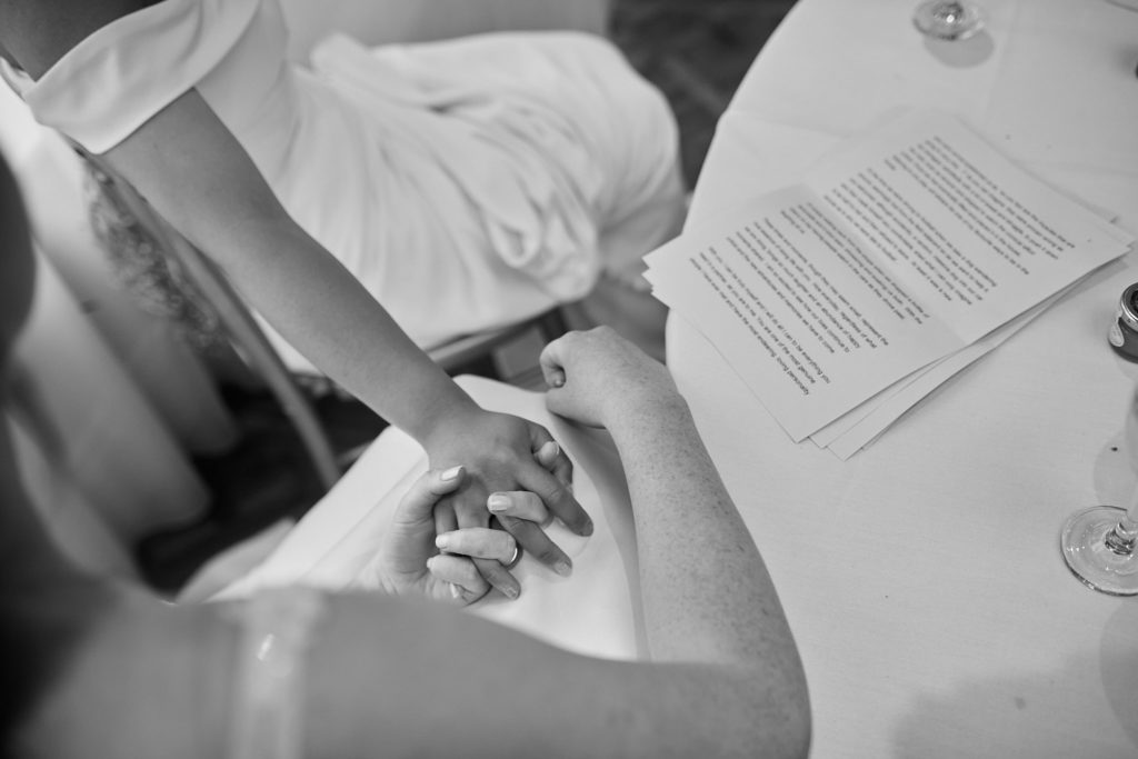 Black and white close-up of two people holding hands at the table