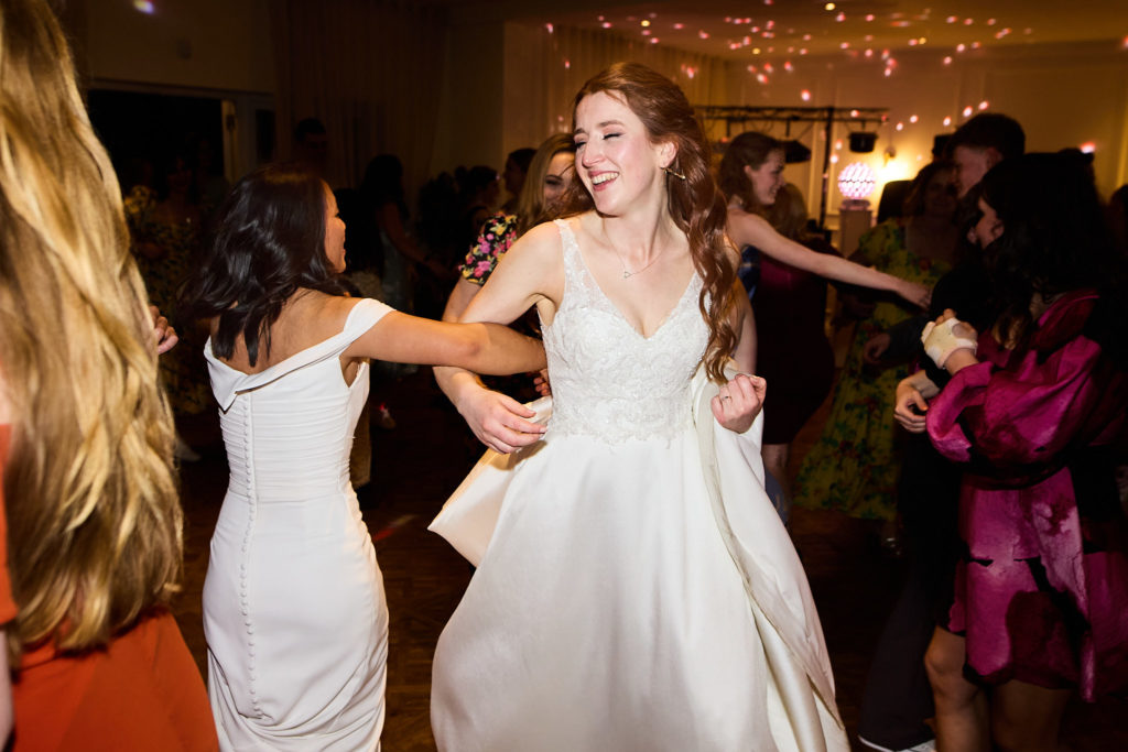 Two brides dancing with their guests at their LGBTQ wedding reception