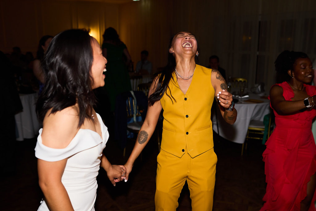 Bride dancing hand in hand with a guest in a yellow suit