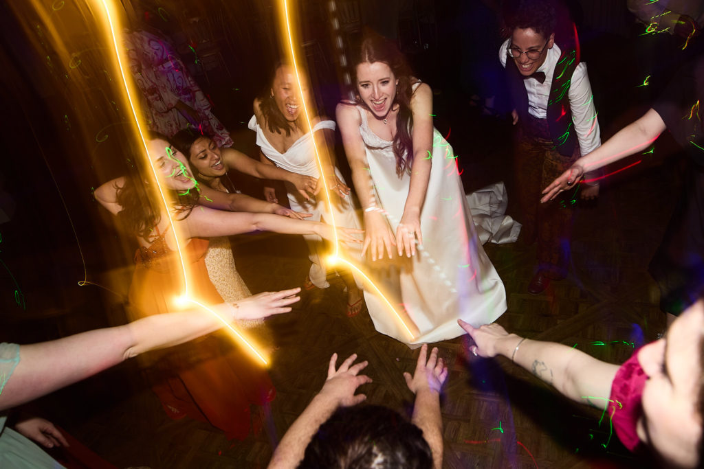 Bride dancing in the middle of a circle of guests among streaks of light