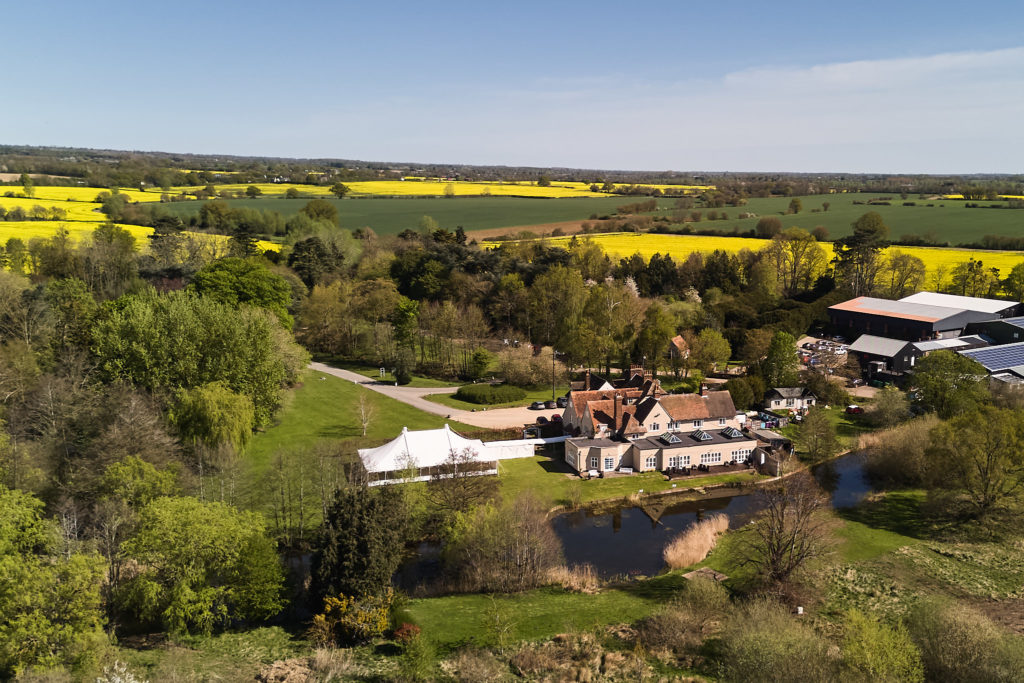 Aerial drone photo of Prested Hall surrounded by fields of yellow rapeseed