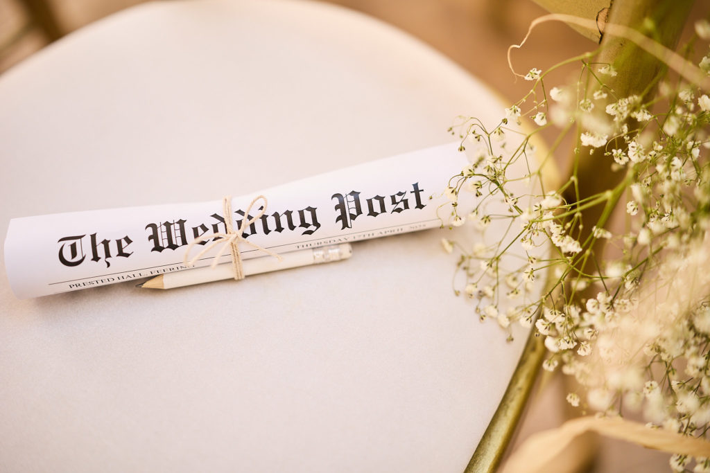 Rolled copy of "The Wedding Post" newspaper on a chair