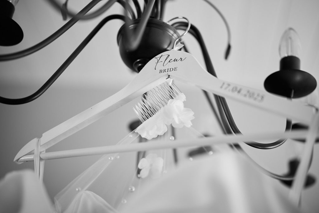 Black and white photo of wedding dresses hanging from a chandelier