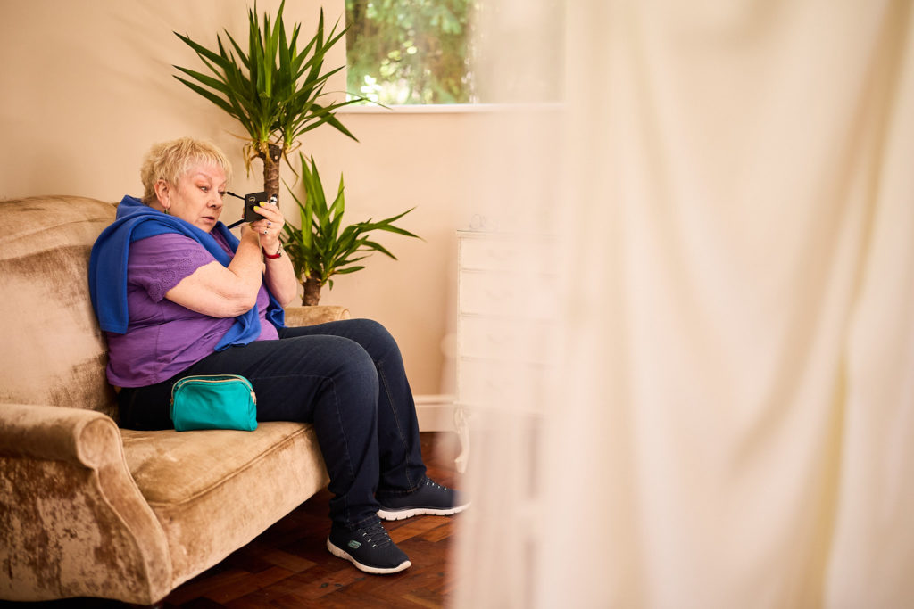 Older guest sitting on a sofa taking a photo