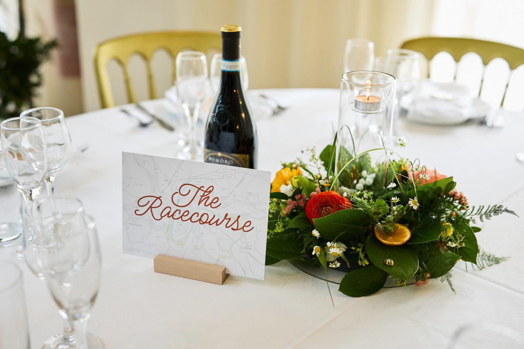 Table name card reading "The Rollercoaster" beside a flower centrepiece