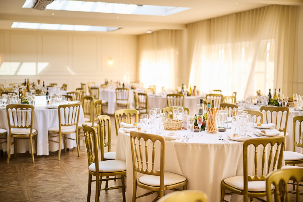 Reception room set with round tables and gold chairs at Prested Hall