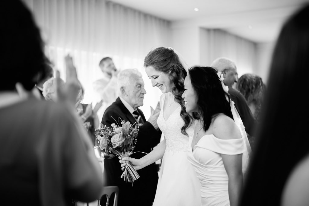Black and white photo of a bride hugging a guest