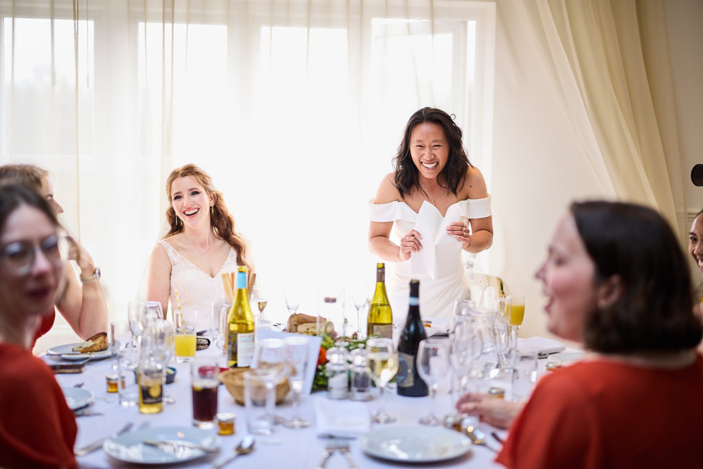 Two brides laughing at the top table during the speeches at their LGBTQ wedding
