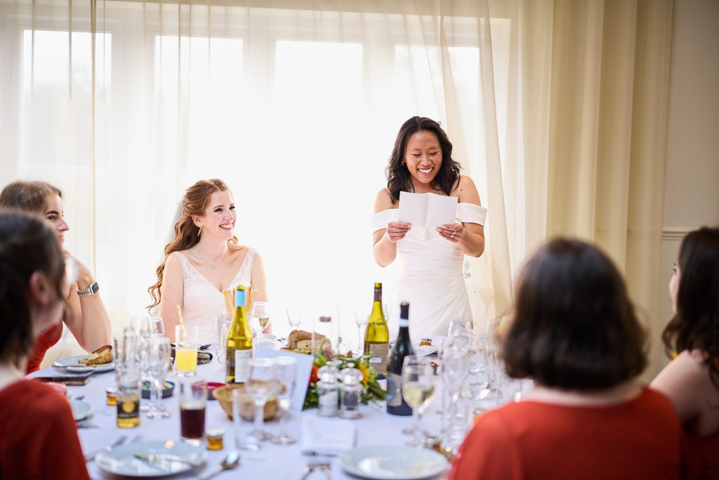 Bride reading her speech as her wife listens