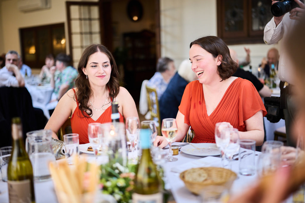 Bridesmaids in red laughing at the table