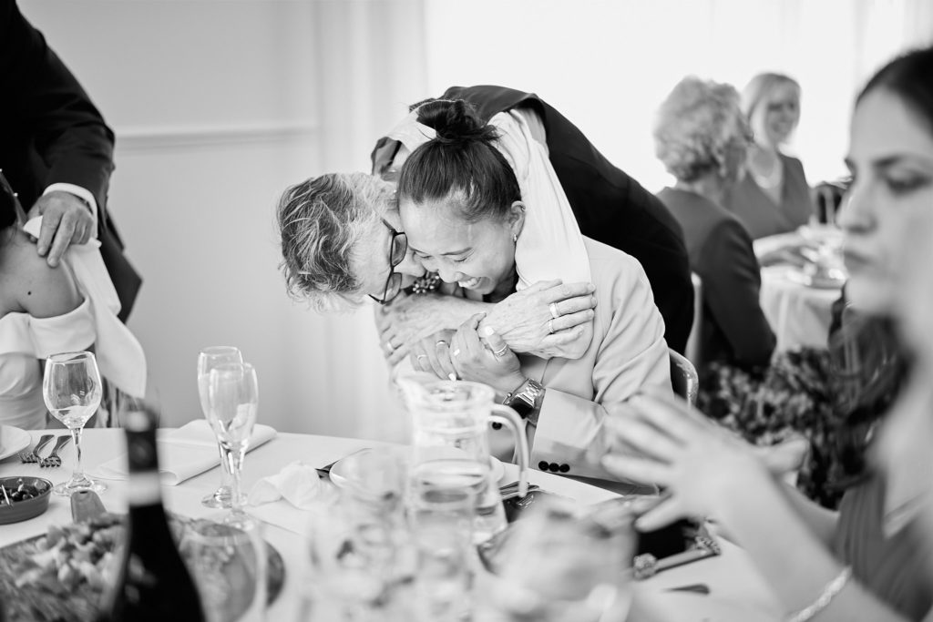 Black and white photo of two guests hugging at the table