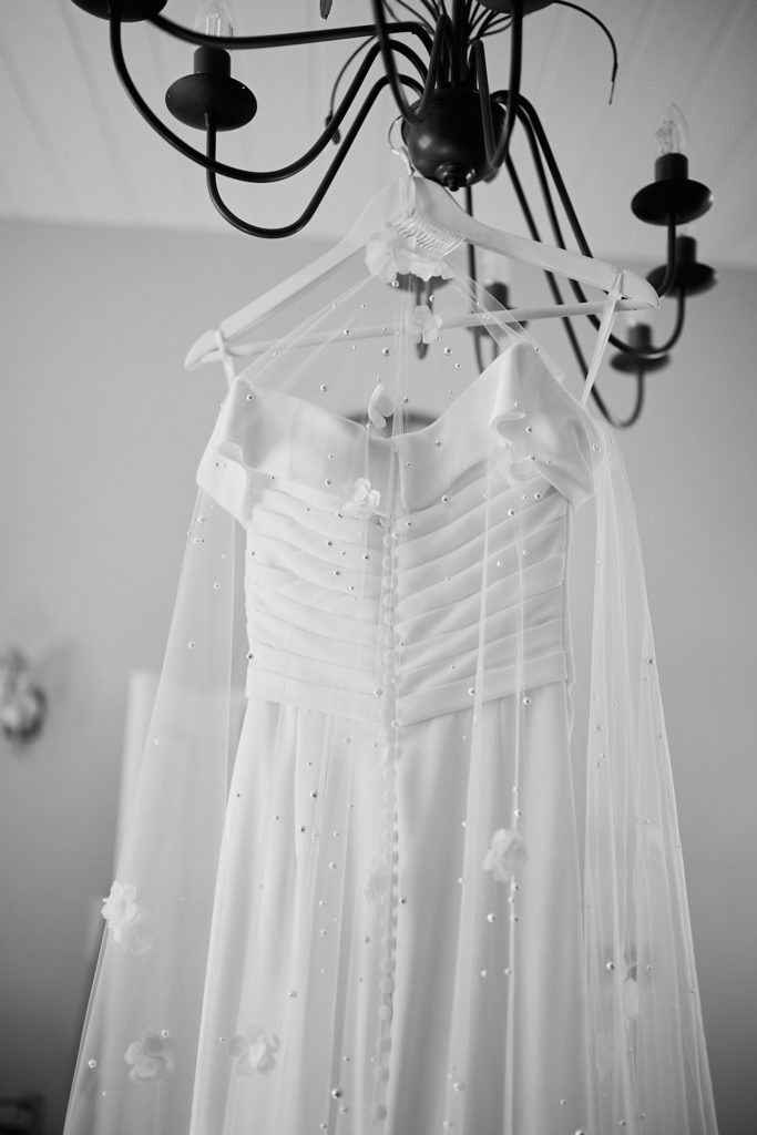 Black and white photo of a wedding dress hanging from a chandelier