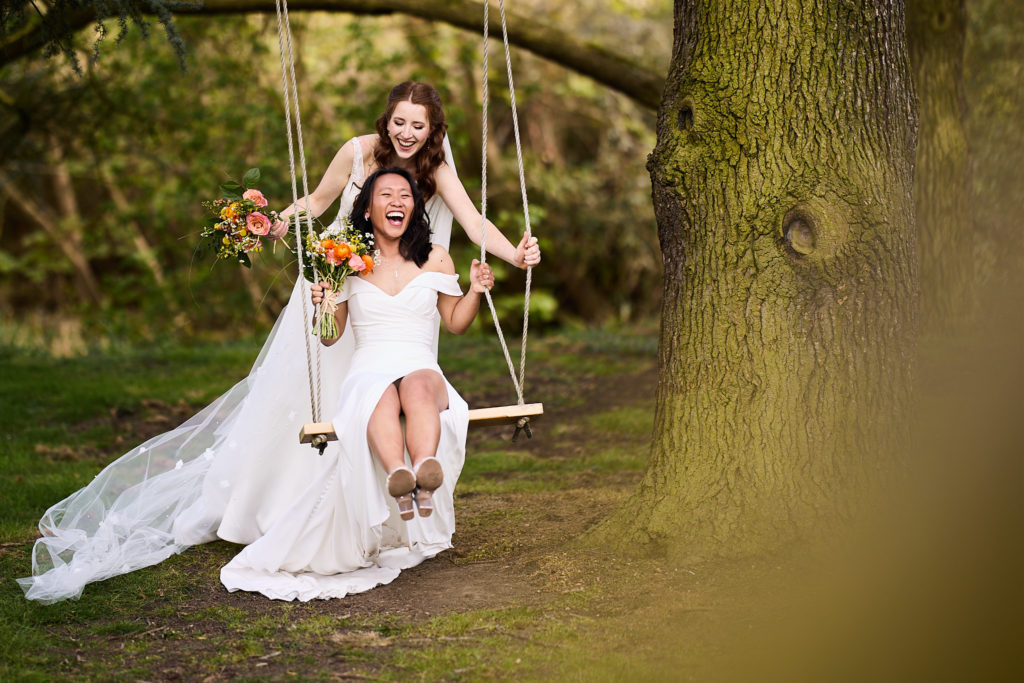 Bride pushing her wife on a tree swing at Prested Hall