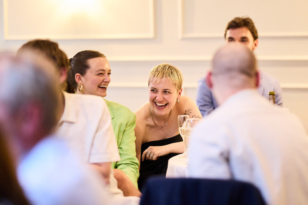 Wedding guests laughing together during the speeches