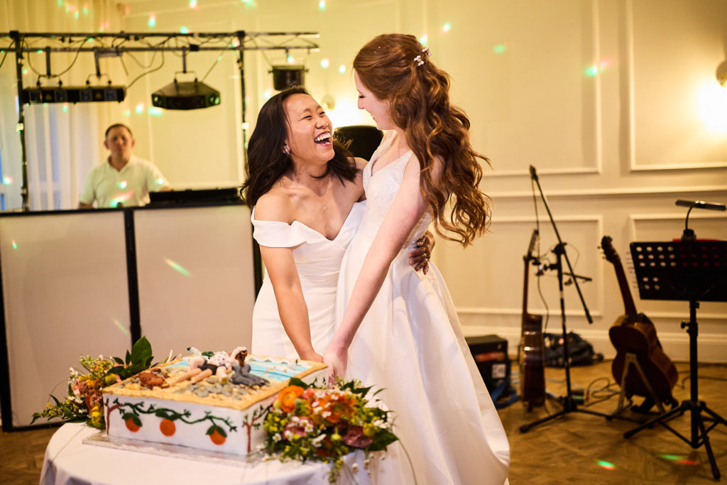 Two brides cutting their wedding cake at their same-sex wedding at Prested Hall