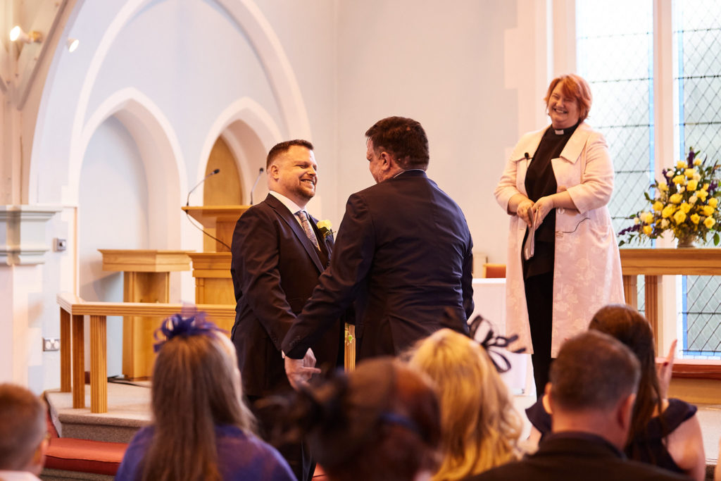 Two grooms facing each other during their church wedding in Windsor