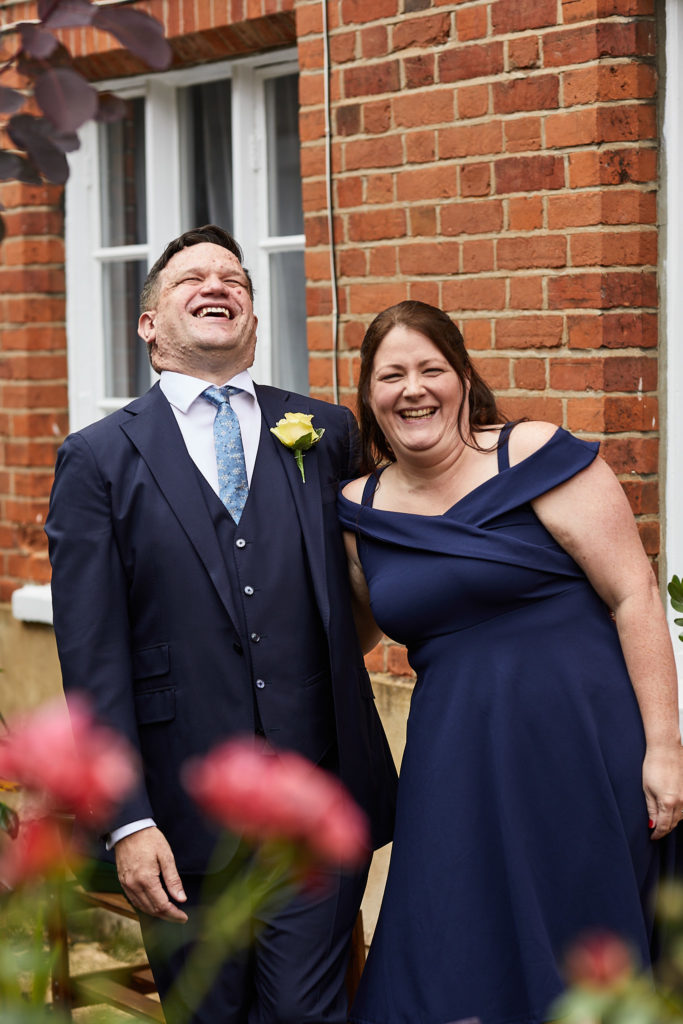Groom laughing with his best woman in a navy dress