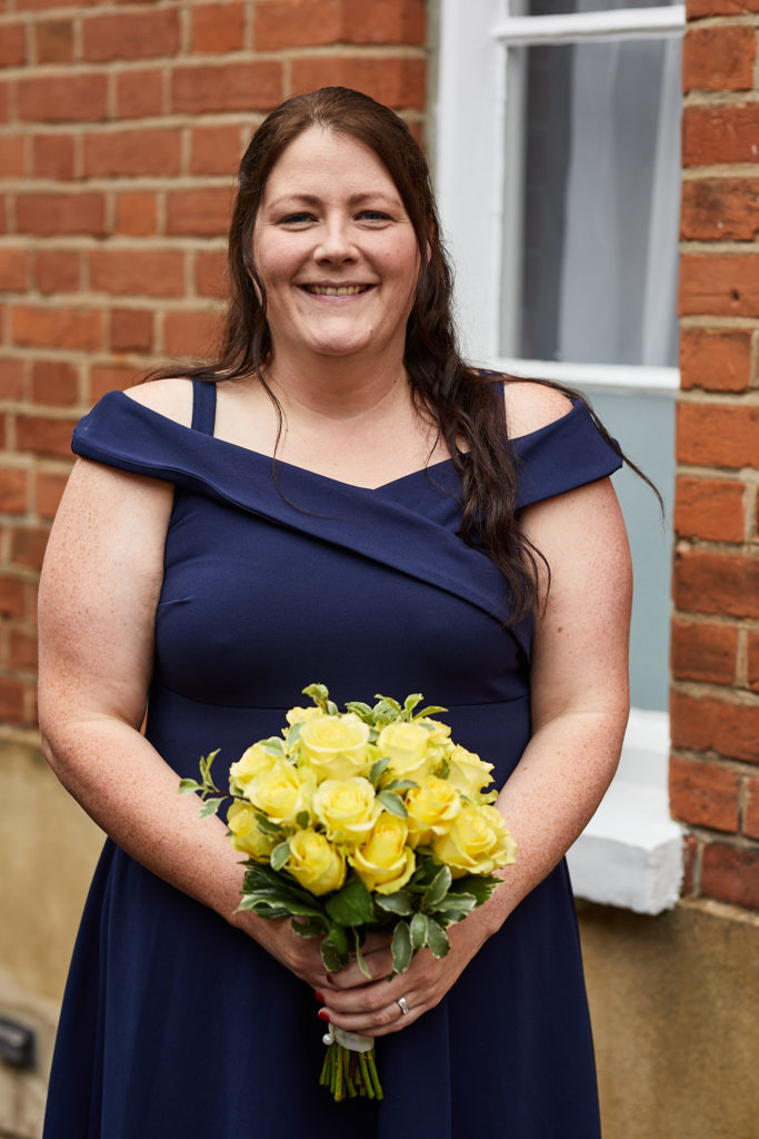 Best woman in a navy dress holding a bouquet of yellow roses