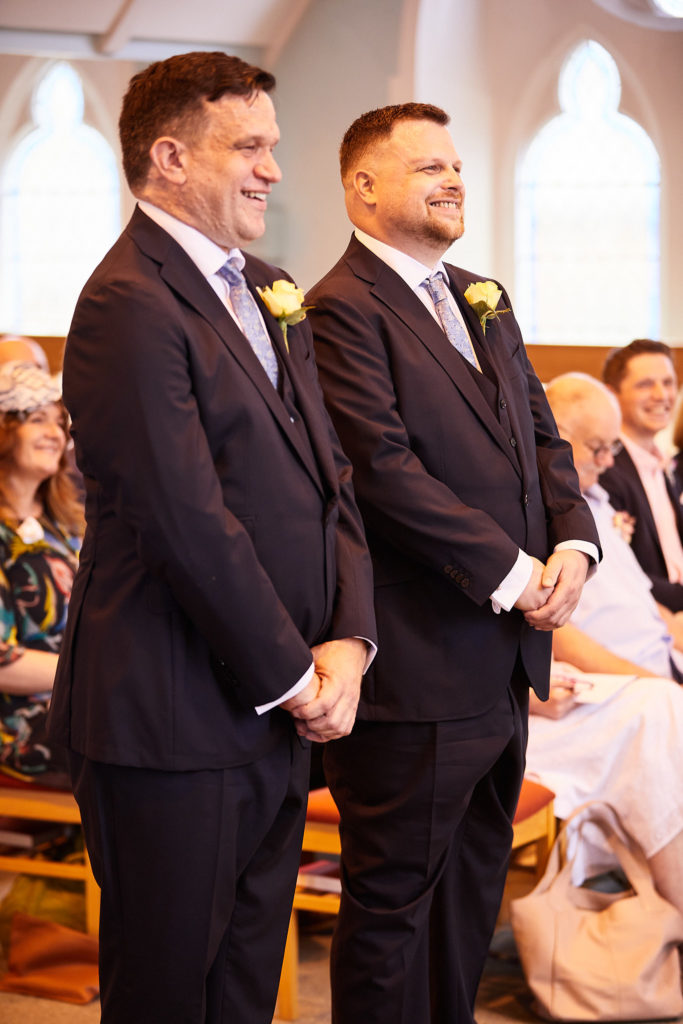 Two grooms smiling as they stand together during their wedding ceremony