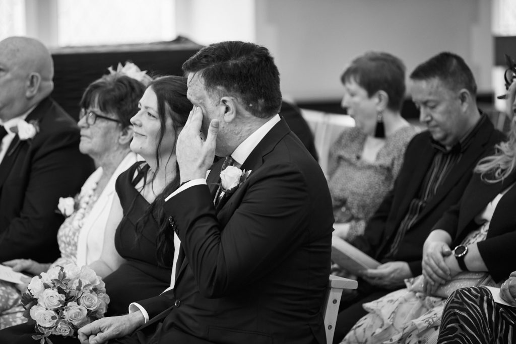 Black and white photo of guests wiping away tears during the ceremony