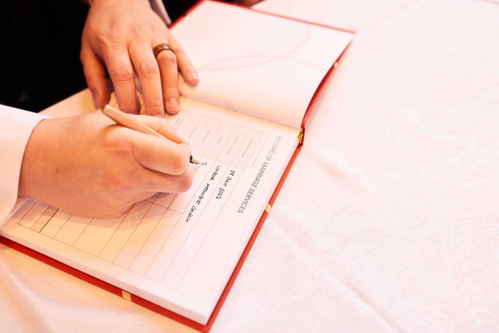 Close-up of a hand signing the marriage register