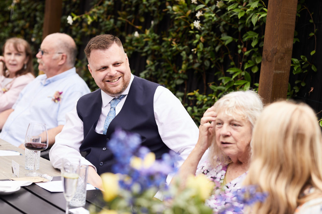 Groom laughing with guests at the table