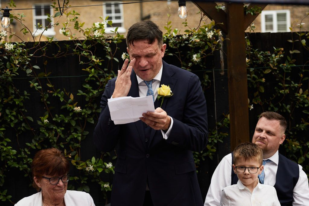 Groom wiping his eye as he reads his speech
