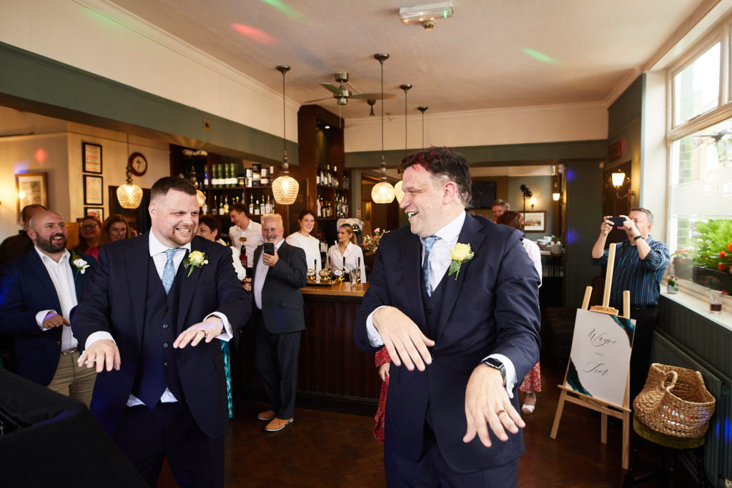 Two grooms making their entrance into the pub for their evening reception