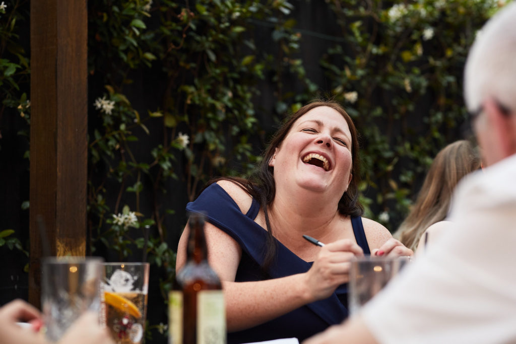 Wedding guest in a navy dress laughing at the table