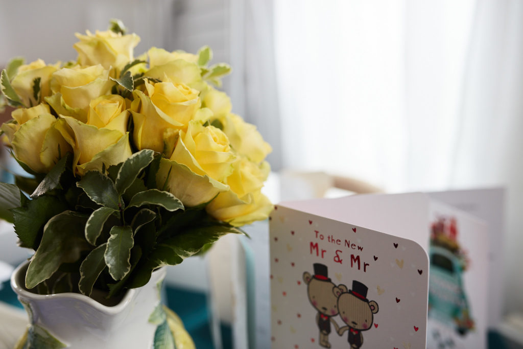 Yellow roses in a vase beside a wedding card