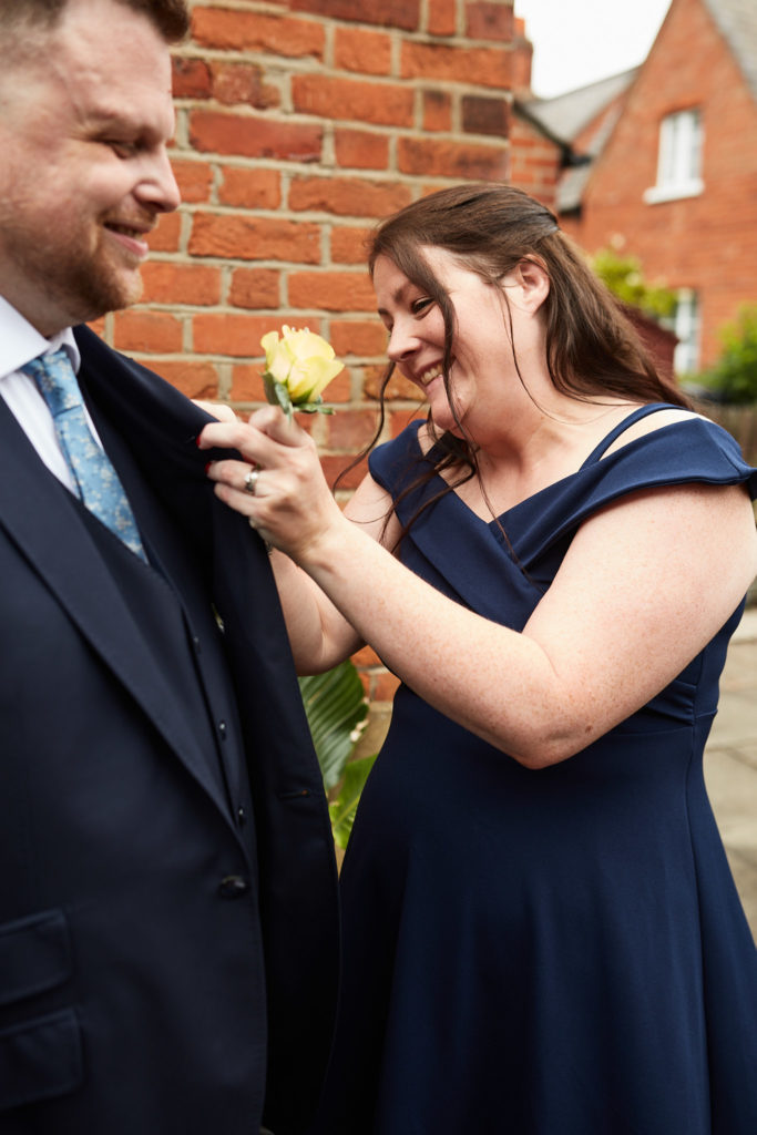 Best woman pinning a yellow rose buttonhole on a groom