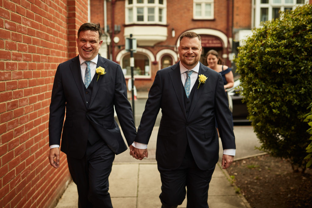 Two grooms walking hand in hand to their wedding in Windsor