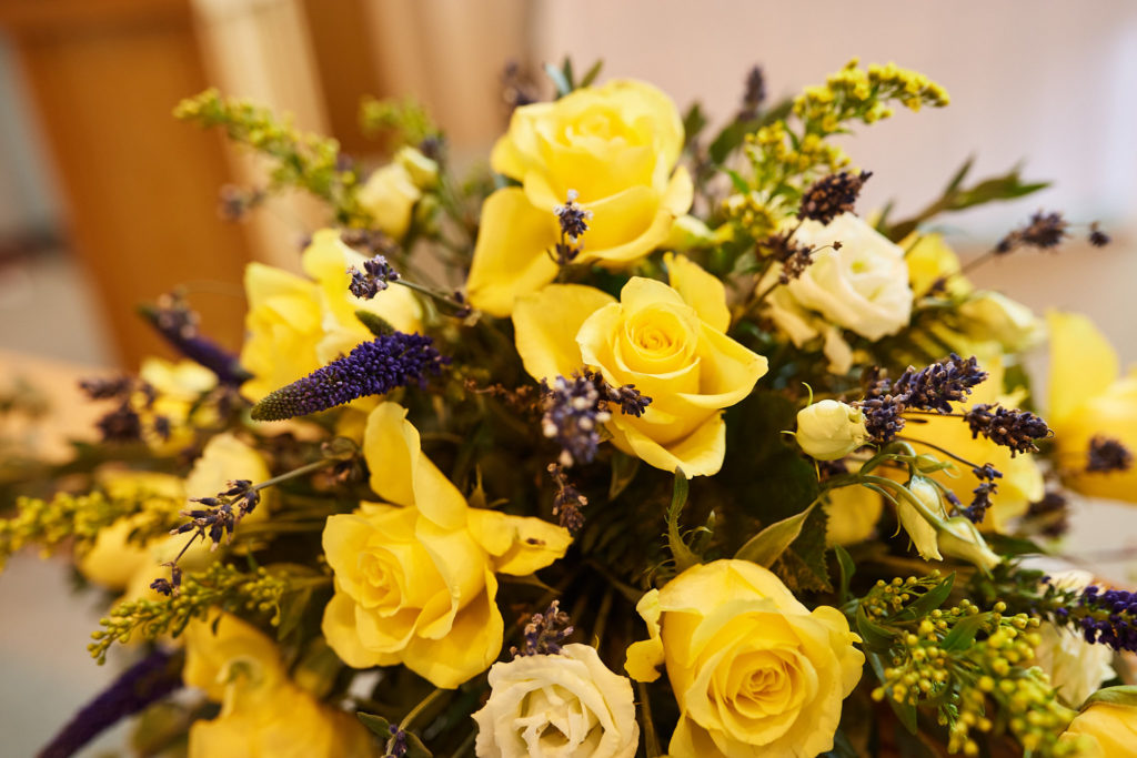 Arrangement of yellow roses and purple flowers