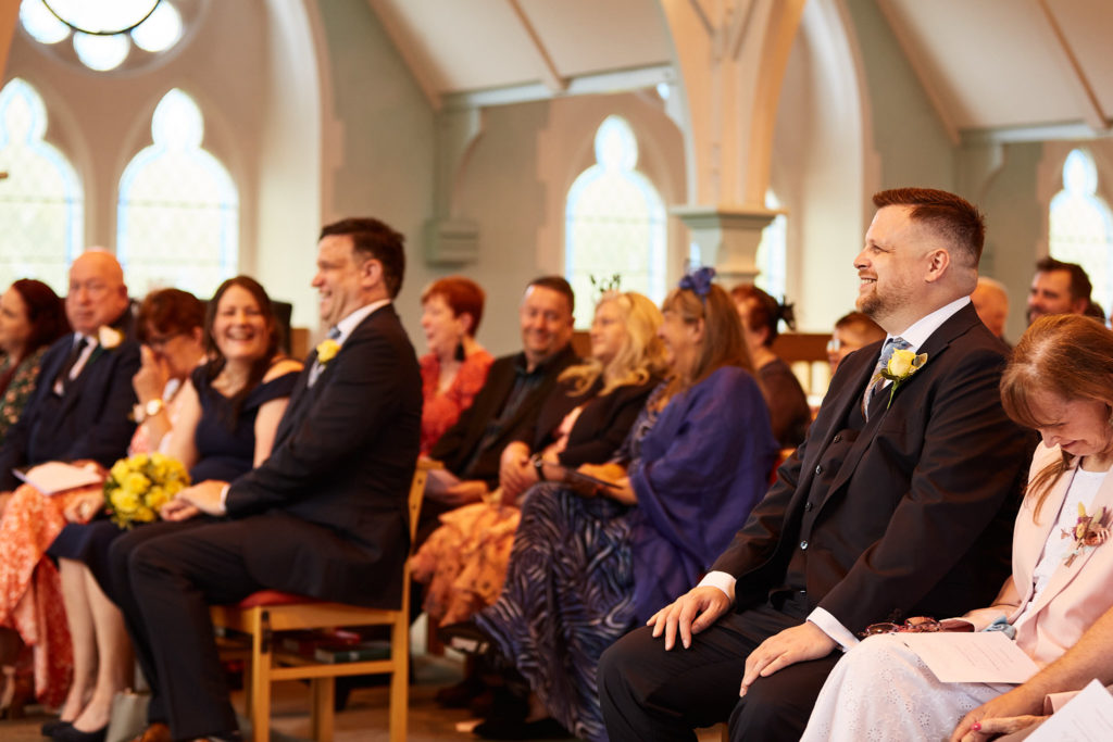 Two grooms seated with their guests during the church ceremony