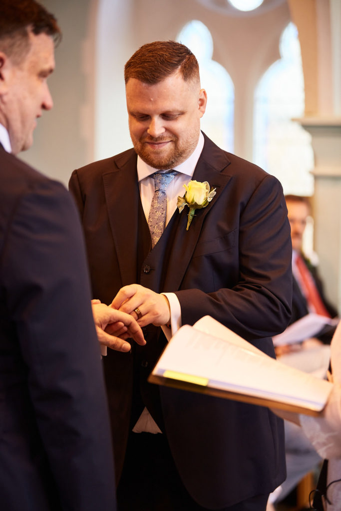 Groom placing a wedding ring on his husband's finger