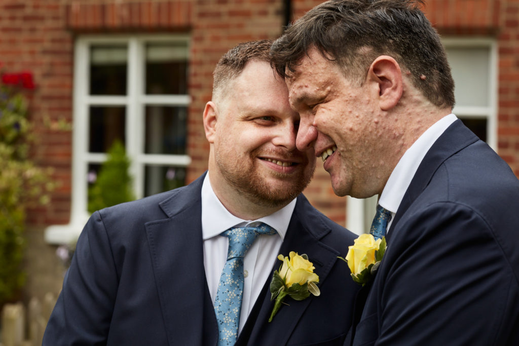 Two grooms smiling forehead to forehead