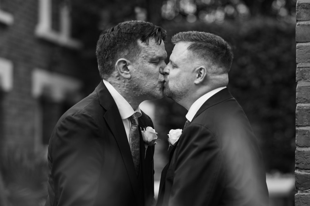 Black and white photo of the two grooms kissing