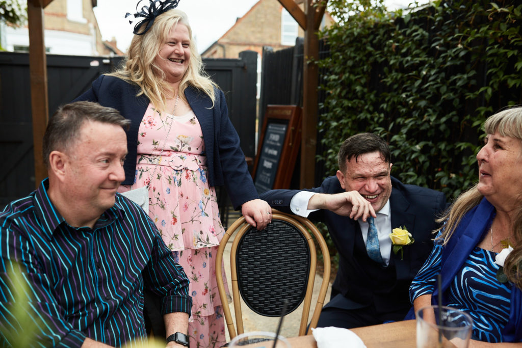 Wedding guests laughing together in the pub garden