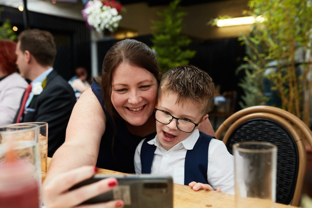 Woman taking a selfie with a young page boy at the table