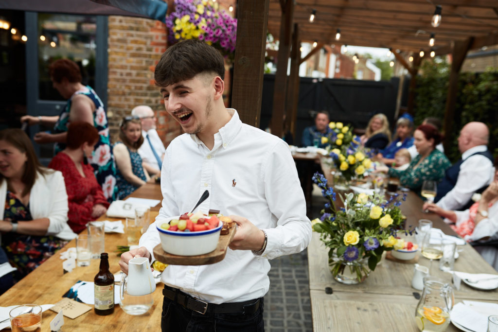 Waiter serving food to guests in the pub garden